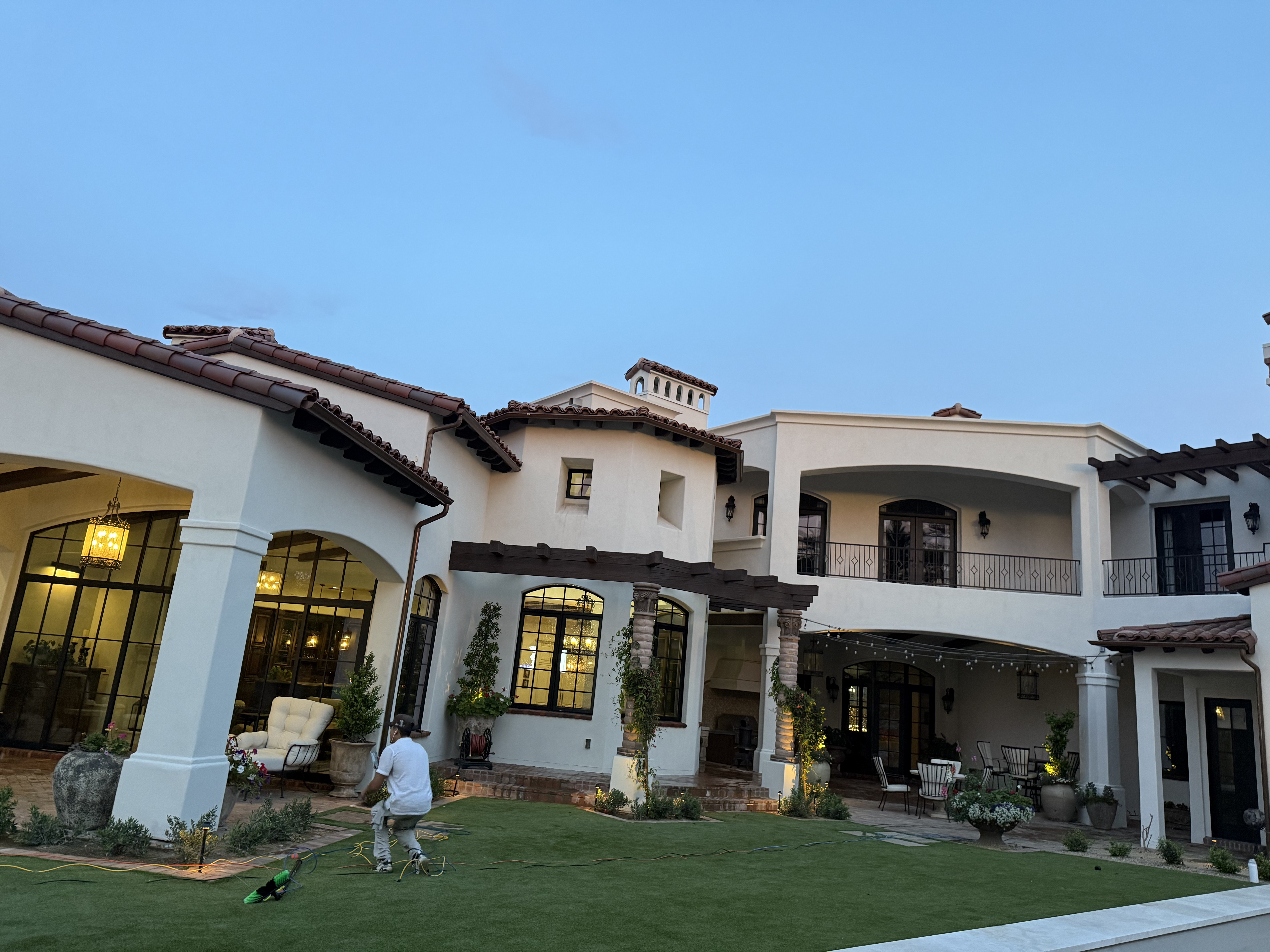Technician pressure washing luxury Spanish estate at dusk