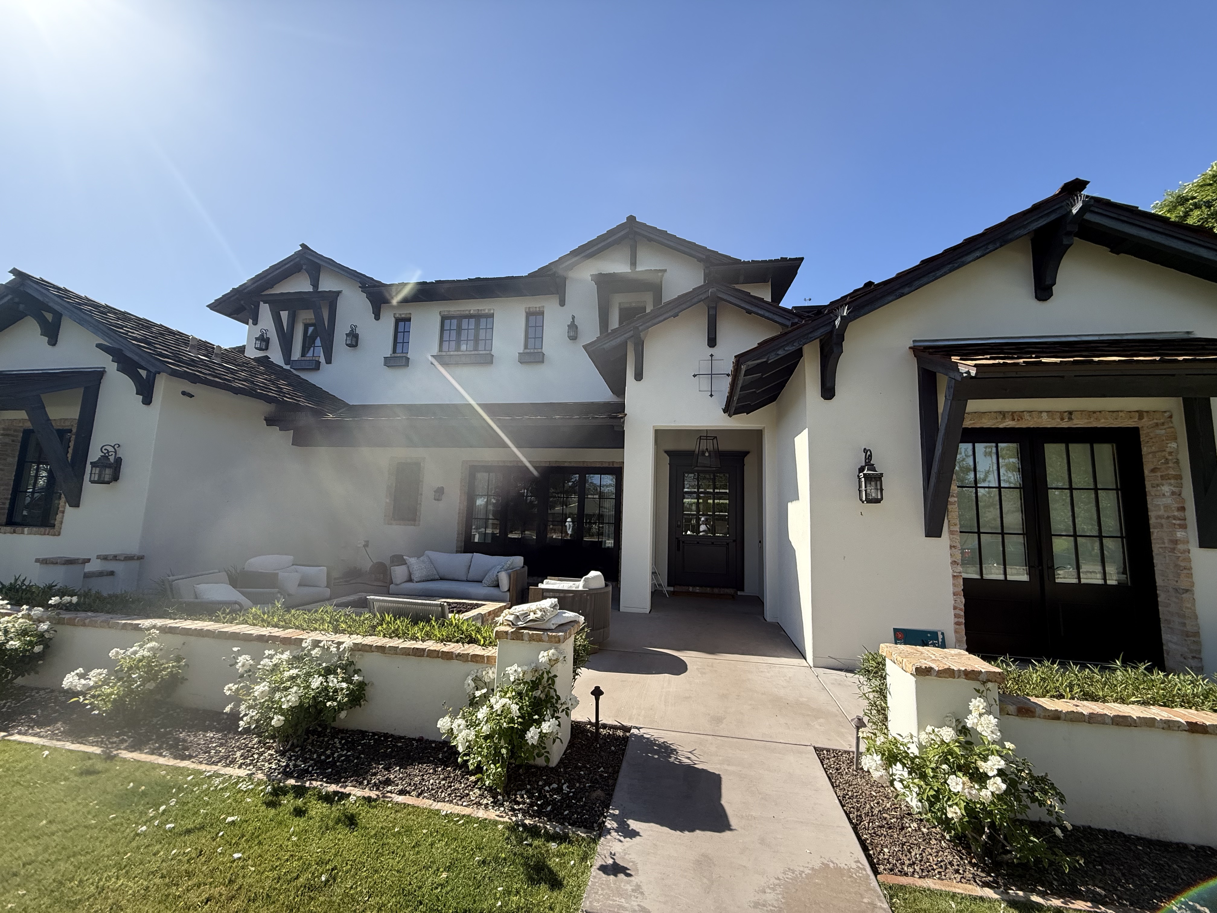 Spanish white stucco home with rose garden and black accents