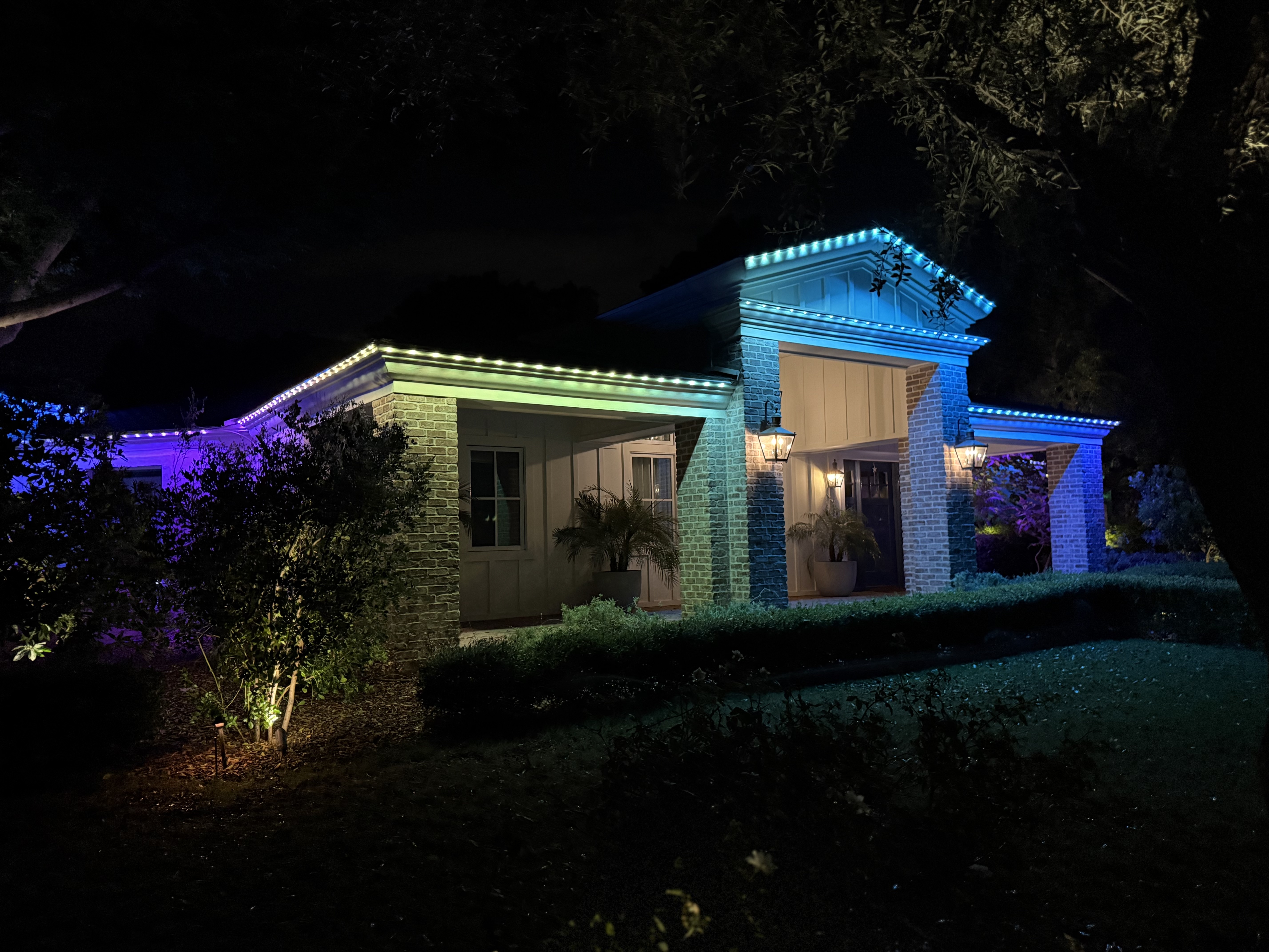 Colorful LED roofline lighting on brick home at night