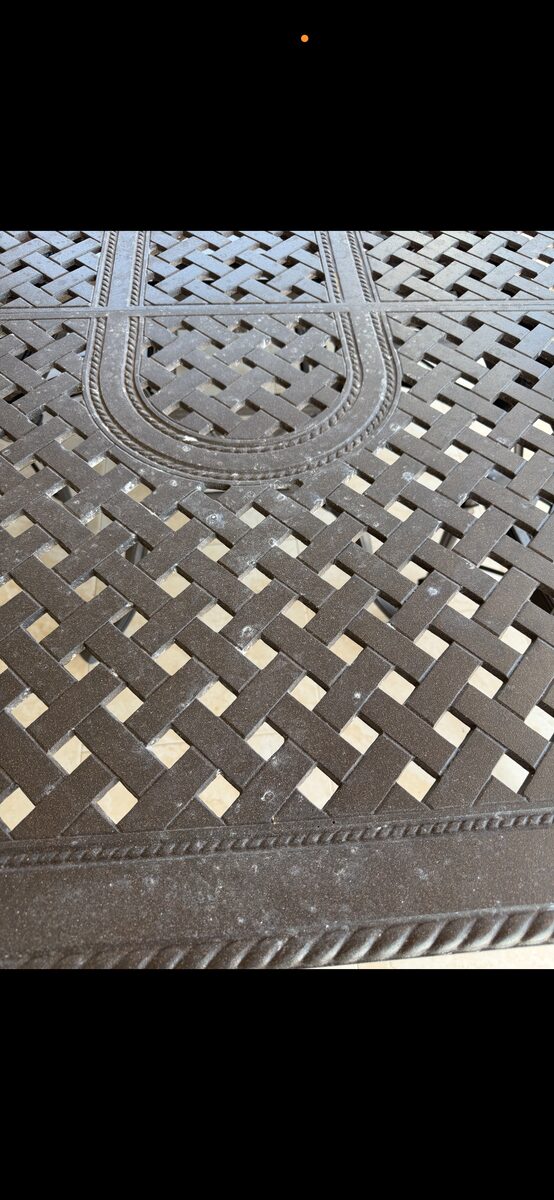 Close-up of white calcium and hard-water spotting embedded in cast-aluminum basketweave patio table pattern
