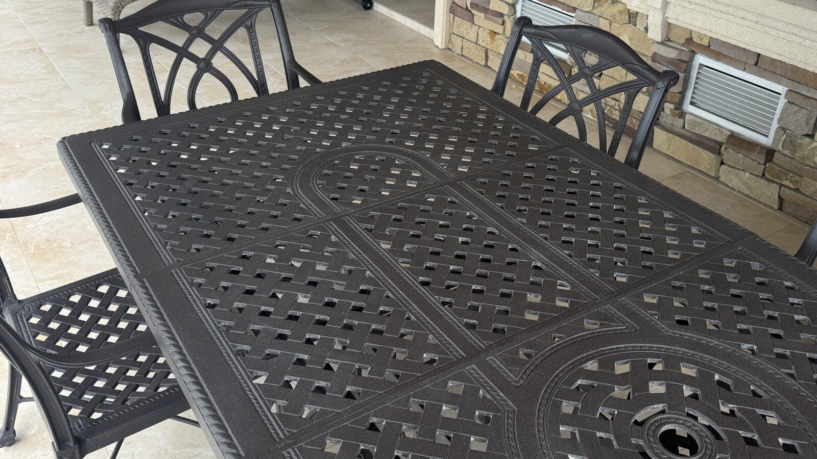 Cast-aluminum patio table and chair set with calcium deposits visible across the woven metal surface before professional cleaning